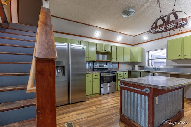 kitchen with appliances with stainless steel finishes, a textured ceiling, light wood-type flooring, and green cabinets