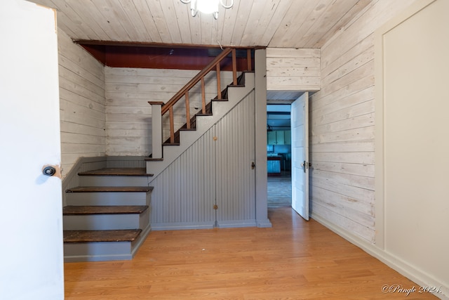 stairway with hardwood / wood-style flooring, wooden walls, and wooden ceiling