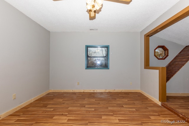 unfurnished room featuring lofted ceiling, a textured ceiling, and light wood-type flooring