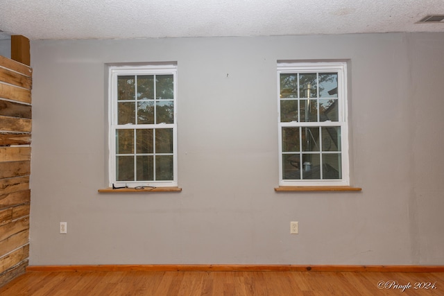 empty room with a textured ceiling and light hardwood / wood-style floors