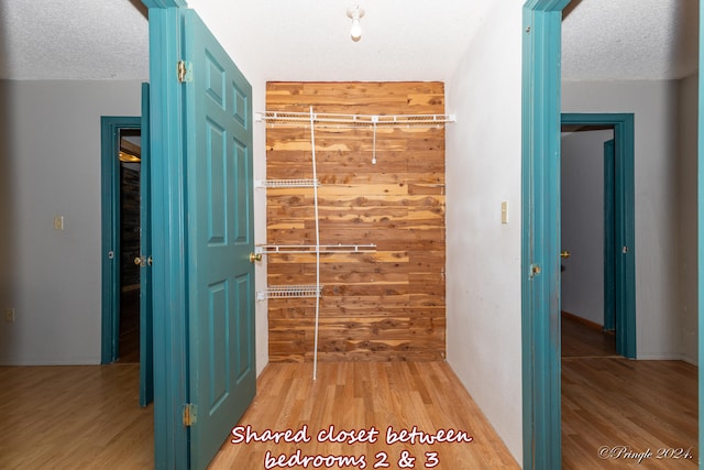 hall with a textured ceiling and light hardwood / wood-style floors