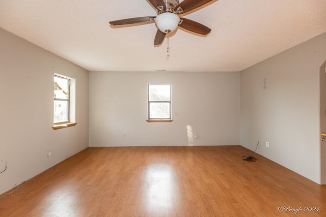 empty room with light hardwood / wood-style floors, a textured ceiling, plenty of natural light, and ceiling fan