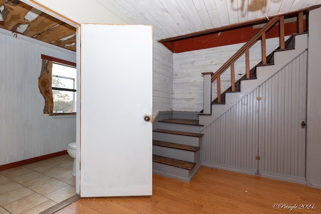 stairway with wood ceiling, hardwood / wood-style flooring, and wood walls