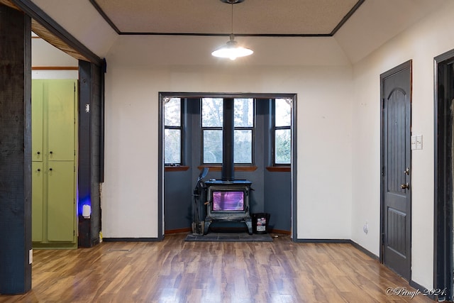 foyer entrance with a wood stove, hardwood / wood-style floors, lofted ceiling, and crown molding