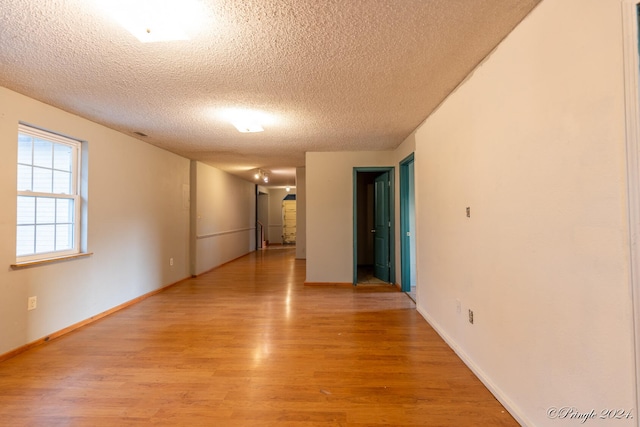 empty room with a textured ceiling and light hardwood / wood-style floors