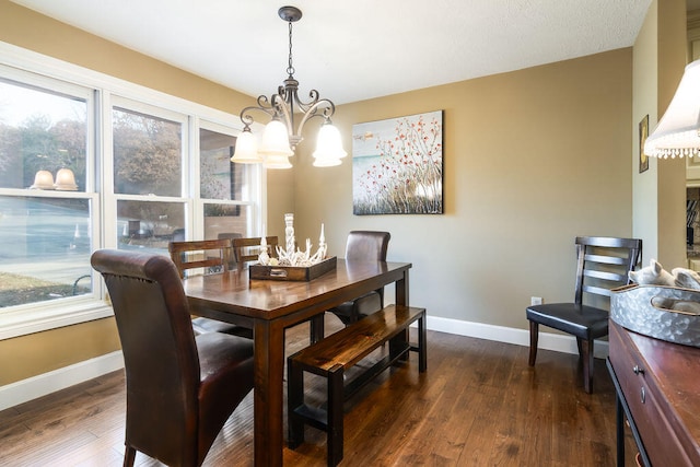 dining space with dark hardwood / wood-style floors and an inviting chandelier