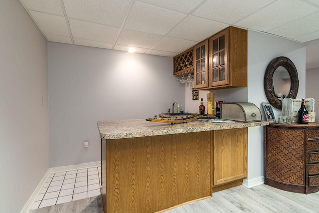 bar with a drop ceiling and light wood-type flooring