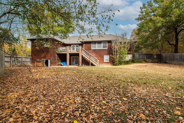 rear view of house featuring a wooden deck and a lawn