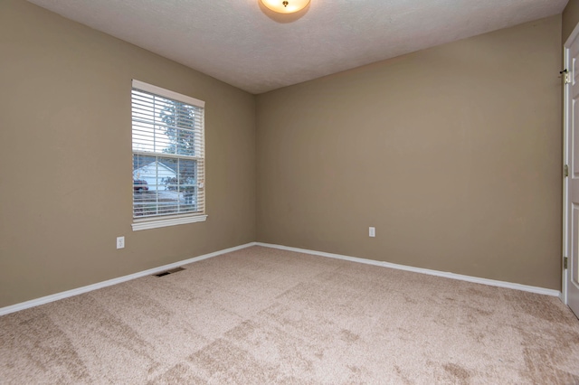 carpeted empty room with a textured ceiling