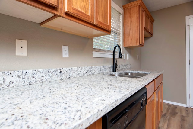 kitchen featuring black dishwasher, sink, light stone counters, and dark hardwood / wood-style flooring