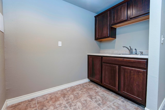 kitchen with light tile patterned flooring, dark brown cabinetry, and sink