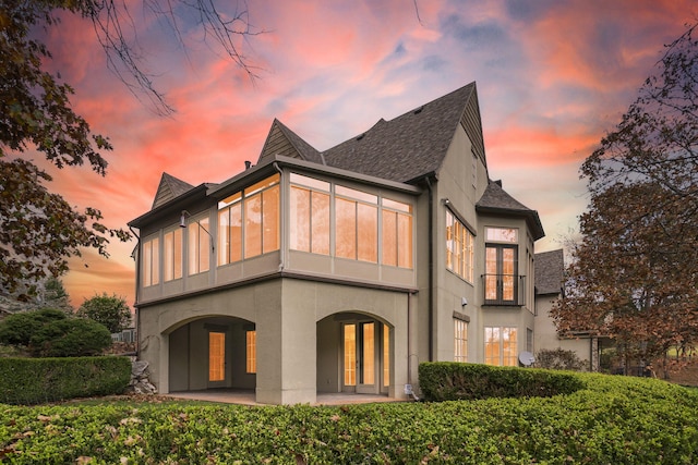 back house at dusk with a patio and french doors