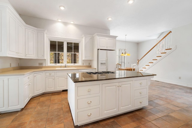 kitchen with sink, a center island, white refrigerator with ice dispenser, and white cabinets