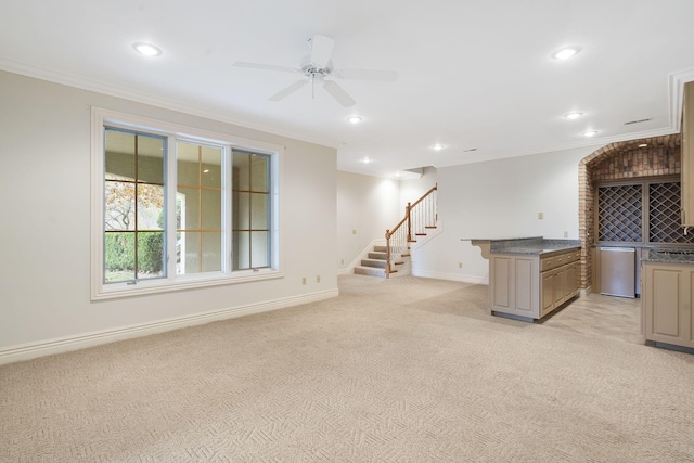 interior space with dishwasher, a kitchen island, ornamental molding, light colored carpet, and ceiling fan