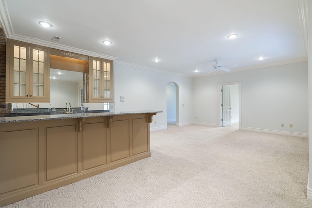 kitchen featuring crown molding, dark stone countertops, and light colored carpet