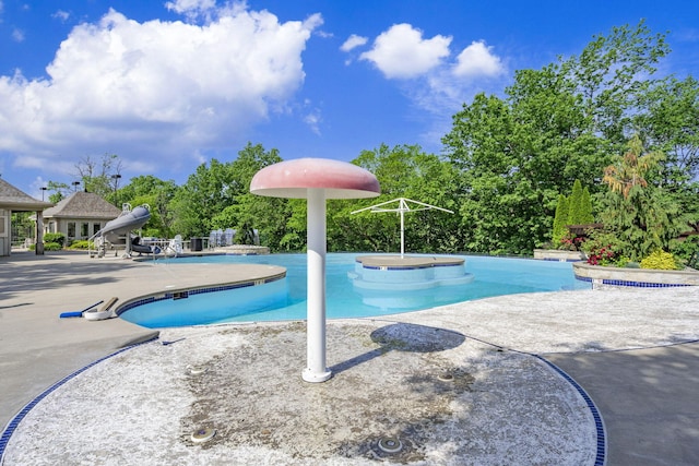 view of swimming pool with a water slide, a patio, and a jacuzzi