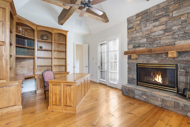 unfurnished office featuring light hardwood / wood-style flooring, a stone fireplace, lofted ceiling with beams, and ceiling fan