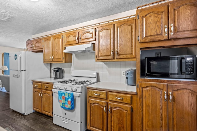 kitchen with a textured ceiling, dark hardwood / wood-style flooring, white appliances, and backsplash