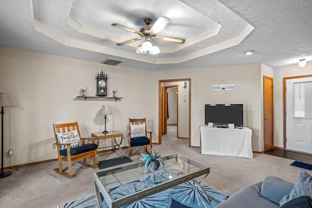 carpeted living room with ceiling fan, a raised ceiling, and a textured ceiling