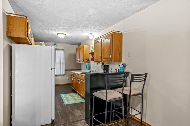 kitchen with a kitchen breakfast bar, dark hardwood / wood-style flooring, tasteful backsplash, a textured ceiling, and white fridge