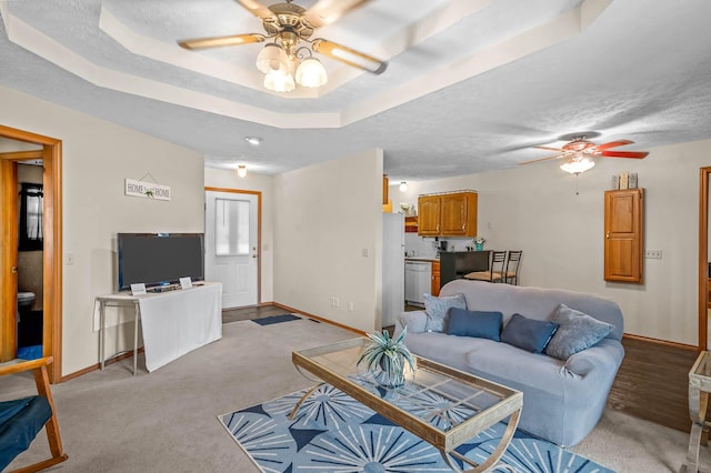 carpeted living room featuring a tray ceiling, ceiling fan, and a textured ceiling