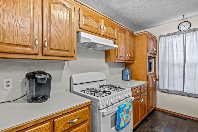 kitchen with backsplash, white gas stove, dark wood-type flooring, and a textured ceiling