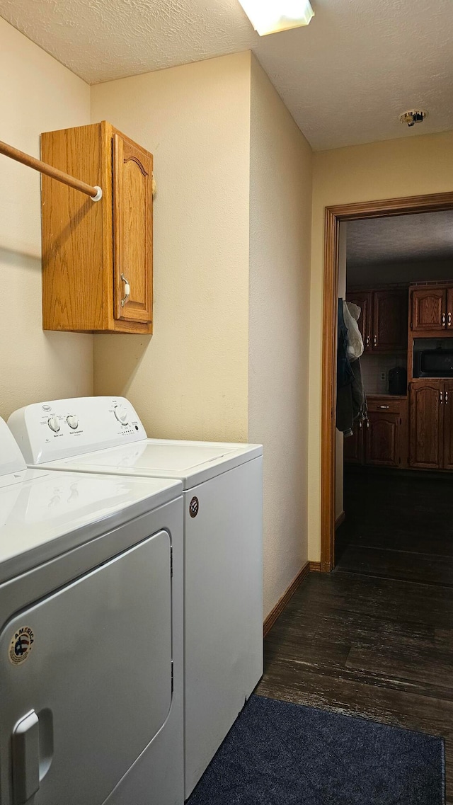 laundry room with cabinets, a textured ceiling, dark hardwood / wood-style floors, and washing machine and clothes dryer