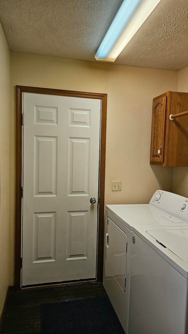 washroom featuring cabinets, washing machine and dryer, and a textured ceiling