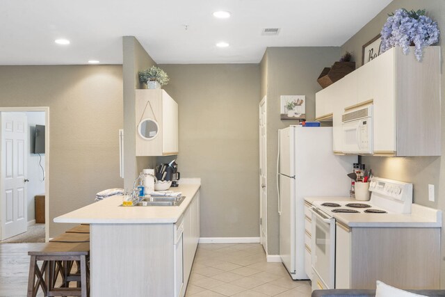 kitchen featuring white appliances, light tile patterned floors, sink, kitchen peninsula, and a breakfast bar