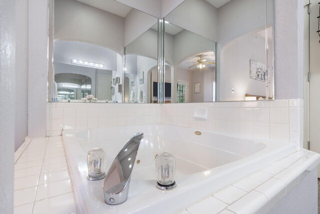 bathroom featuring tiled bath and ceiling fan