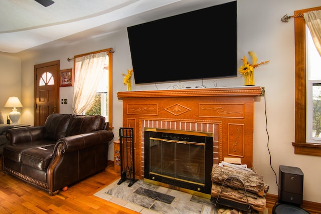 living room with hardwood / wood-style flooring, a wealth of natural light, and a brick fireplace