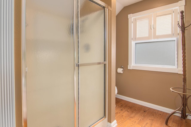 bathroom featuring a shower with door, hardwood / wood-style floors, and toilet