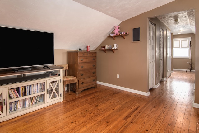 interior space featuring hardwood / wood-style floors, a textured ceiling, and vaulted ceiling