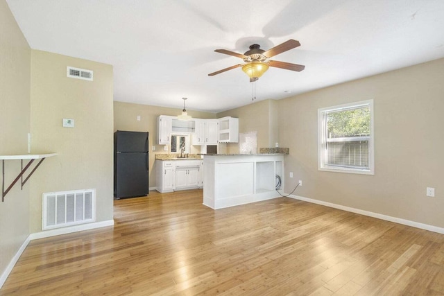 kitchen featuring black refrigerator, kitchen peninsula, sink, white cabinetry, and light hardwood / wood-style floors