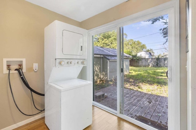 clothes washing area featuring light hardwood / wood-style flooring and stacked washing maching and dryer