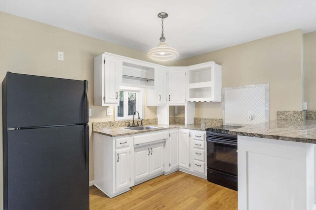 kitchen featuring black appliances, sink, light hardwood / wood-style floors, decorative light fixtures, and white cabinets