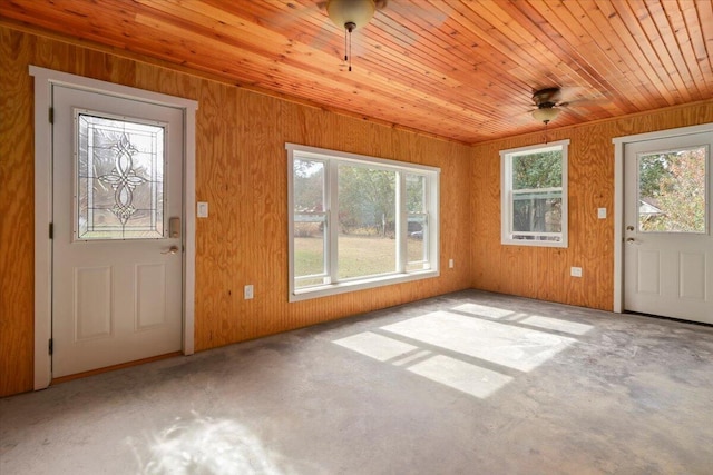 foyer entrance featuring wood walls, wooden ceiling, and a wealth of natural light