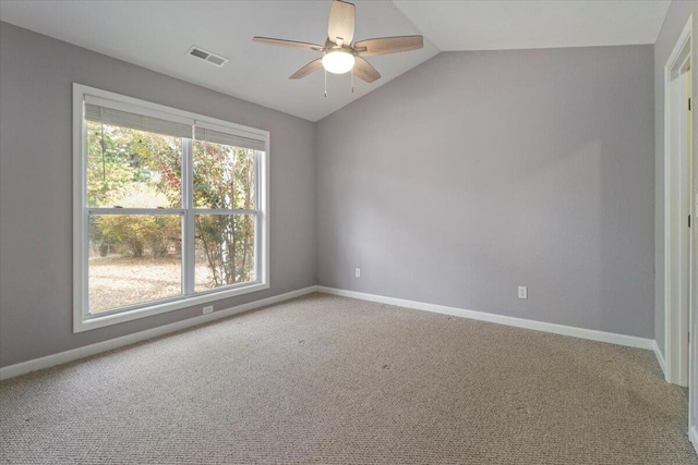 carpeted empty room with ceiling fan, vaulted ceiling, and plenty of natural light