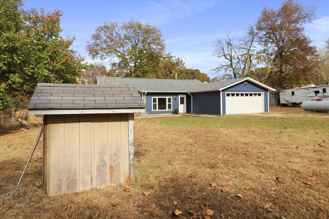 view of front of home with a storage unit, a front lawn, and a garage