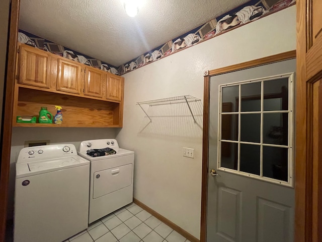 laundry area with washer and clothes dryer, a textured ceiling, light tile patterned floors, and cabinets