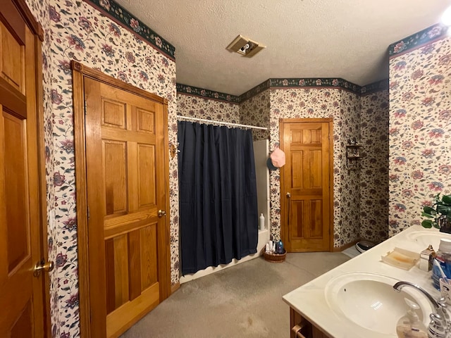 bathroom with shower / tub combo with curtain, vanity, and a textured ceiling