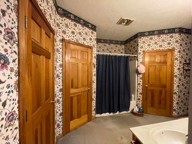 bathroom with vanity, shower / tub combo with curtain, and a textured ceiling