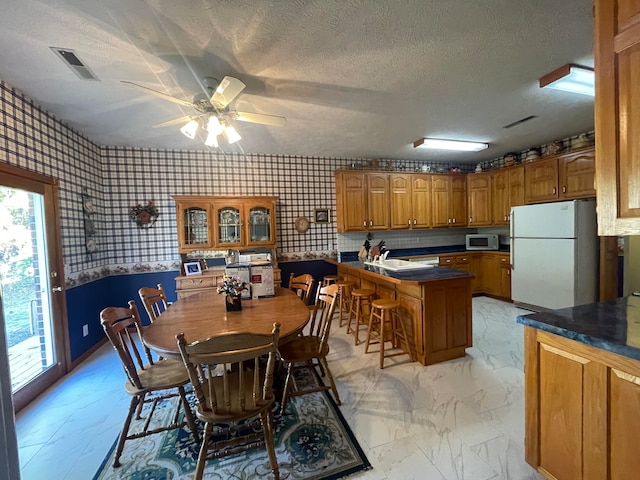 dining space featuring sink, a textured ceiling, and ceiling fan