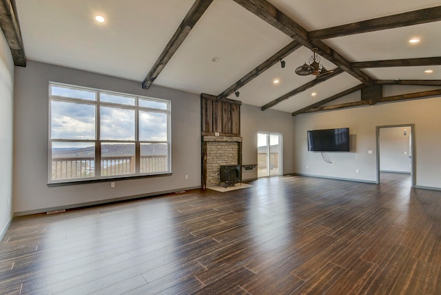 unfurnished living room featuring a wealth of natural light, vaulted ceiling with beams, a wood stove, and dark hardwood / wood-style flooring