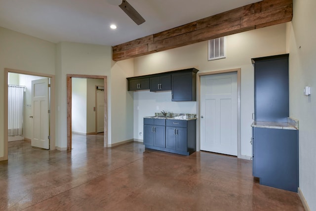 kitchen with beamed ceiling, sink, light stone counters, and ceiling fan