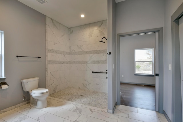 bathroom featuring toilet, wood-type flooring, and tiled shower