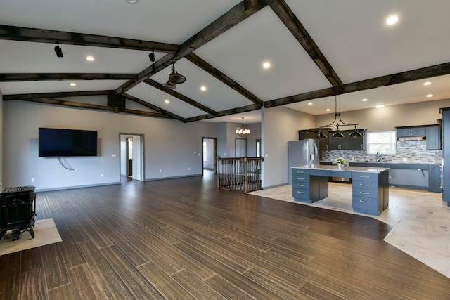 kitchen with light hardwood / wood-style floors, a center island, vaulted ceiling with beams, and pendant lighting