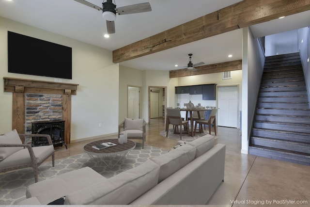 living room featuring a stone fireplace, beamed ceiling, concrete flooring, and ceiling fan