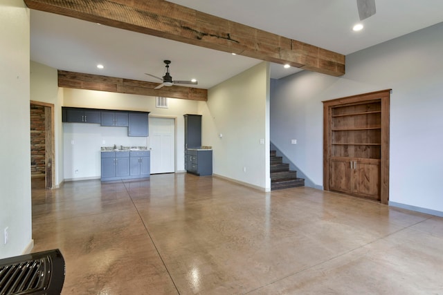 unfurnished living room featuring beamed ceiling, concrete flooring, and ceiling fan