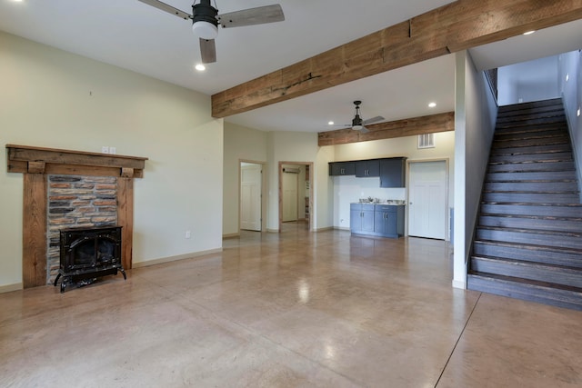 unfurnished living room with beamed ceiling, a wood stove, and concrete flooring